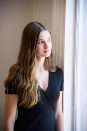 young teen girl looking out bright window